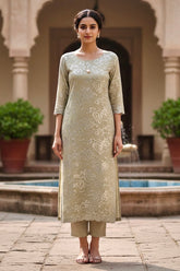Woman in a traditional Kurta outfit standing in front of an architectural structure with plants. Product by umaid Couture