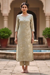 Woman in a traditional Kurta outfit standing in front of an architectural structure with plants. Product by umaid Couture