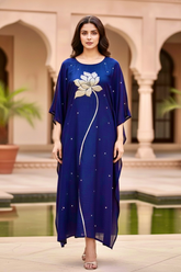 Woman wearing a blue dress with floral design in an outdoor setting. Product by Umaid Couture