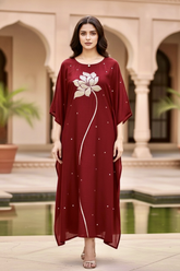 Woman wearing a red dress with white patterns in an outdoor setting with arches and plants. Product by Umaid Couture