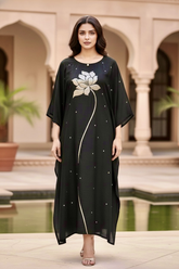 Woman wearing a black dress with floral design in an outdoor setting. Product by Umaid Couture