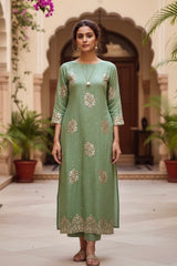 Woman wearing a green traditional Kurta outfit with floral patterns by Umaid Couture, in an outdoor setting.