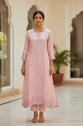 Woman wearing a pink kurta with floral embroidery in an indoor setting. Product by Umaid Couture