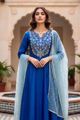 Woman in a blue traditional kurta with a light blue dupatta standing in front of an architectural background. Product by Umaid Couture