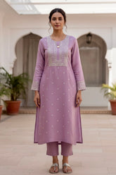 Woman wearing a light purple traditional outfit with intricate designs in an indoor setting. Product by Umaid Couture