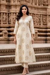 Woman in a cream embroidered Sequins Motifs kurta standing on steps with stone carvings in the background. Product by Umaid Couture