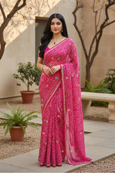Woman in a pink Bandhej saree by Umaid Couture with Gota motifs standing outdoors with plants and a bench in the background