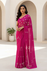 Woman wearing a bright pink saree with a white background. Product By Umaid Couture