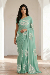Woman wearing a light green saree with beautiful magnolia flower motif on it made by umaid couture.