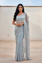 Woman wearing a light blue saree with a white blouse against a neutral background. Product by Umaid Couture.