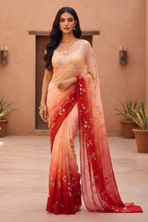 Woman wearing a beige and red saree with floral patterns indoors. Product by Umaid Couture.