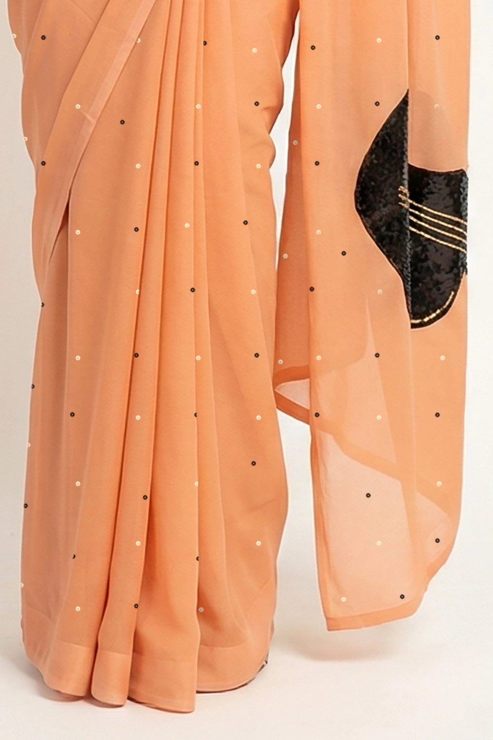 An Indian woman in peach Ragini Saree embellished with Sitar Motifs made of Zari & sequins by craft of Aari-Zardosi, a product of Umaid Couture