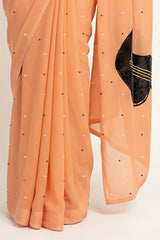An Indian woman in peach Ragini Saree embellished with Sitar Motifs made of Zari & sequins by craft of Aari-Zardosi, a product of Umaid Couture