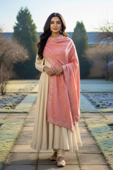 Woman in a pink embroidered stole by Umaid Couture standing on a stone path in a garden background