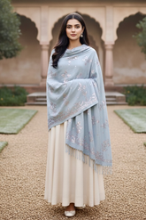 Woman wearing a light blue shawl by Umaid Couture over a white dress in an outdoor setting