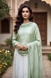 Woman in a pastel green shawl embellished with tiny flowers sequins by Umaid Couture standing in a garden courtyard