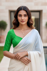 Woman wearing a green blouse and white saree with a blurred background. product by Umaid Couture