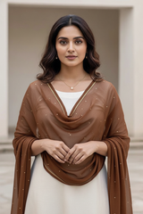 Woman wearing a brown dupatta over a white outfit with a neutral background. product by Umaid Couture