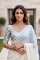 Woman wearing a white saree with a blue blouse in an outdoor setting. product by Umaid Couture