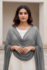 Woman wearing a gray draped scarf over a white top and beige skirt.