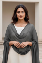 Woman wearing a gray scarf over a white top and beige skirt, standing outdoors. Product by Umaid Couture