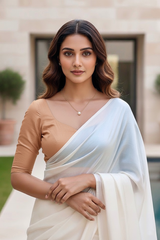 Woman wearing a traditional outfit with a white saree and brown blouse by umaid couture, standing outdoors.