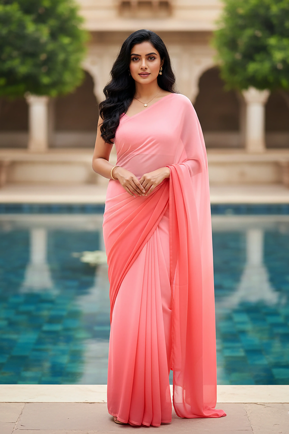 Woman in a pink saree standing by a pool with greenery in the background