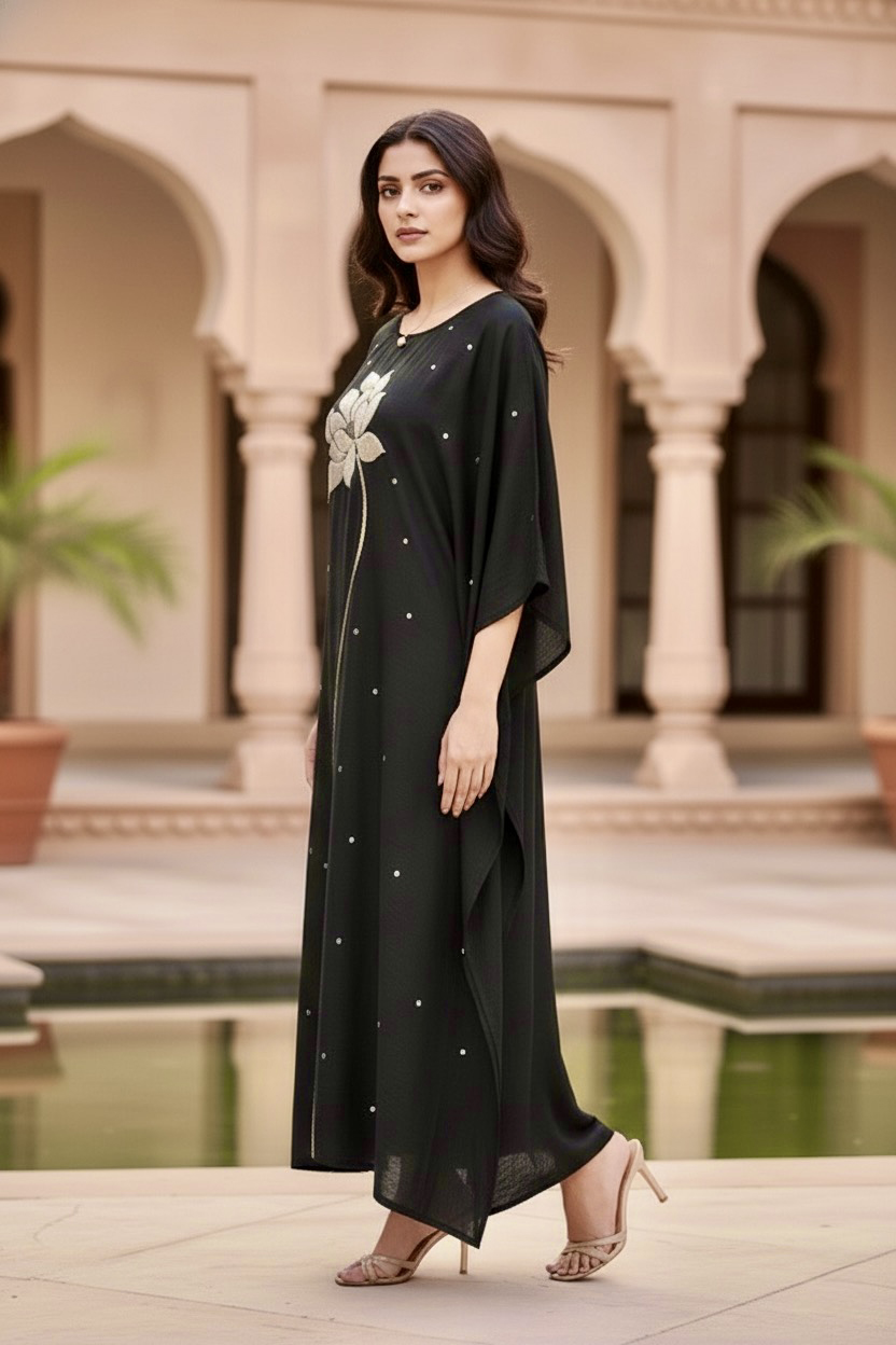 Woman in a black dress standing in front of an architectural background. Product by Umaid Couture