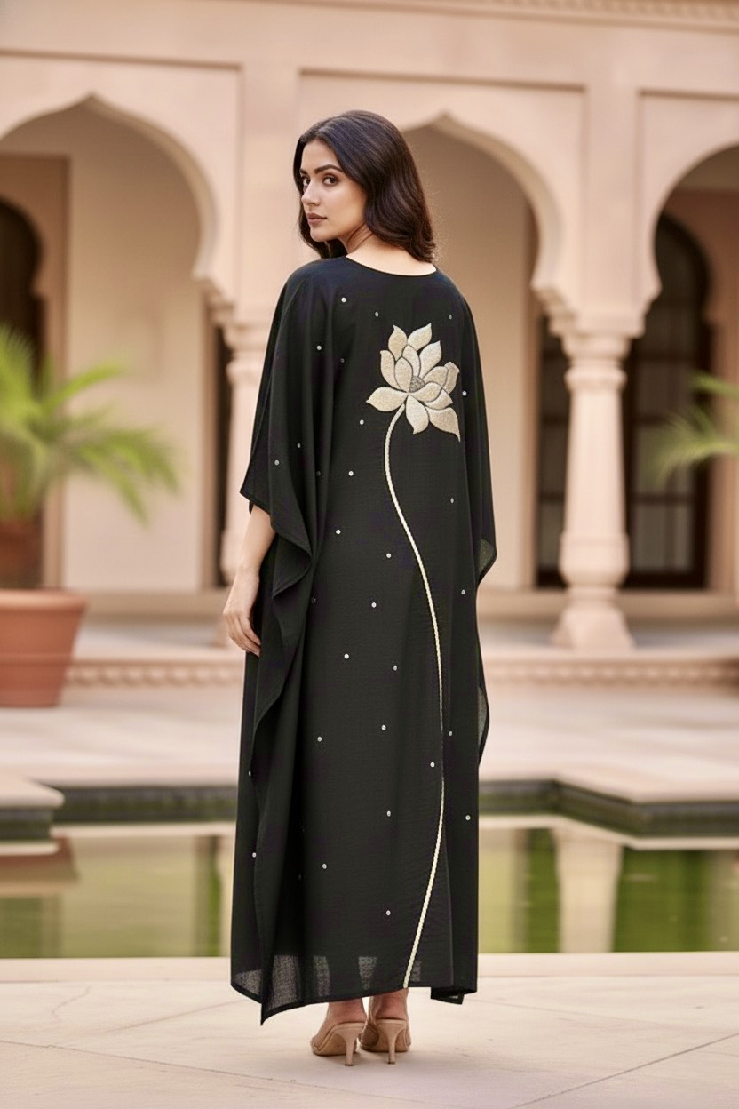 Woman in a black dress standing in front of an architectural background. Product by Umaid Couture