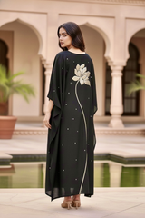 Woman in a black dress standing in front of an architectural background. Product by Umaid Couture