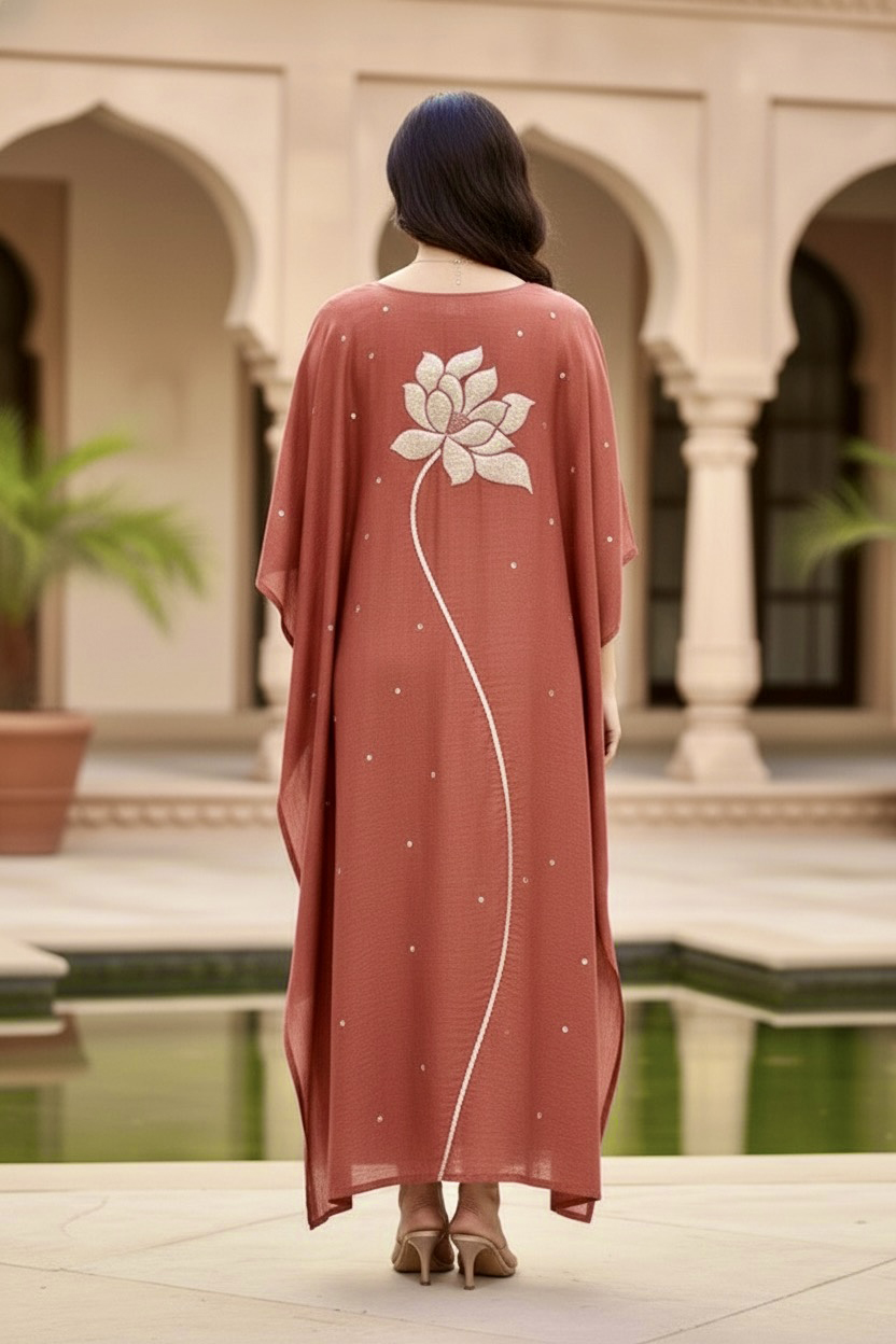 Woman wearing a long, light brown dress with a floral design in an outdoor setting. Product by Umaid Couture