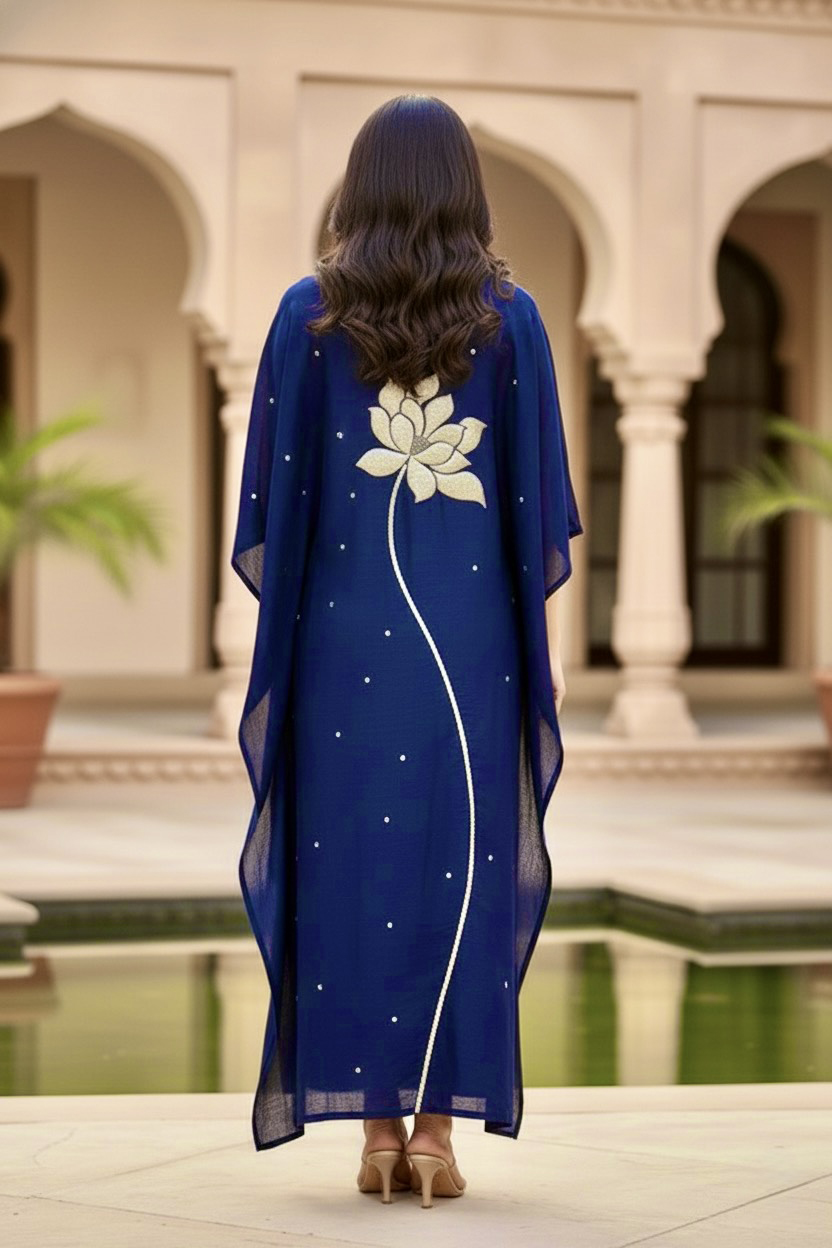Woman wearing a blue dress with a white floral design in an outdoor setting. Product by Umaid Couture