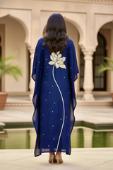 Woman wearing a blue dress with a white floral design in an outdoor setting. Product by Umaid Couture