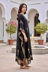 Woman wearing a black kaftan by Umaid Couture  with gold patterns in an outdoor setting