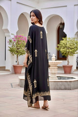Woman wearing a black kaftan by Umaid Couture  with gold patterns in an outdoor setting