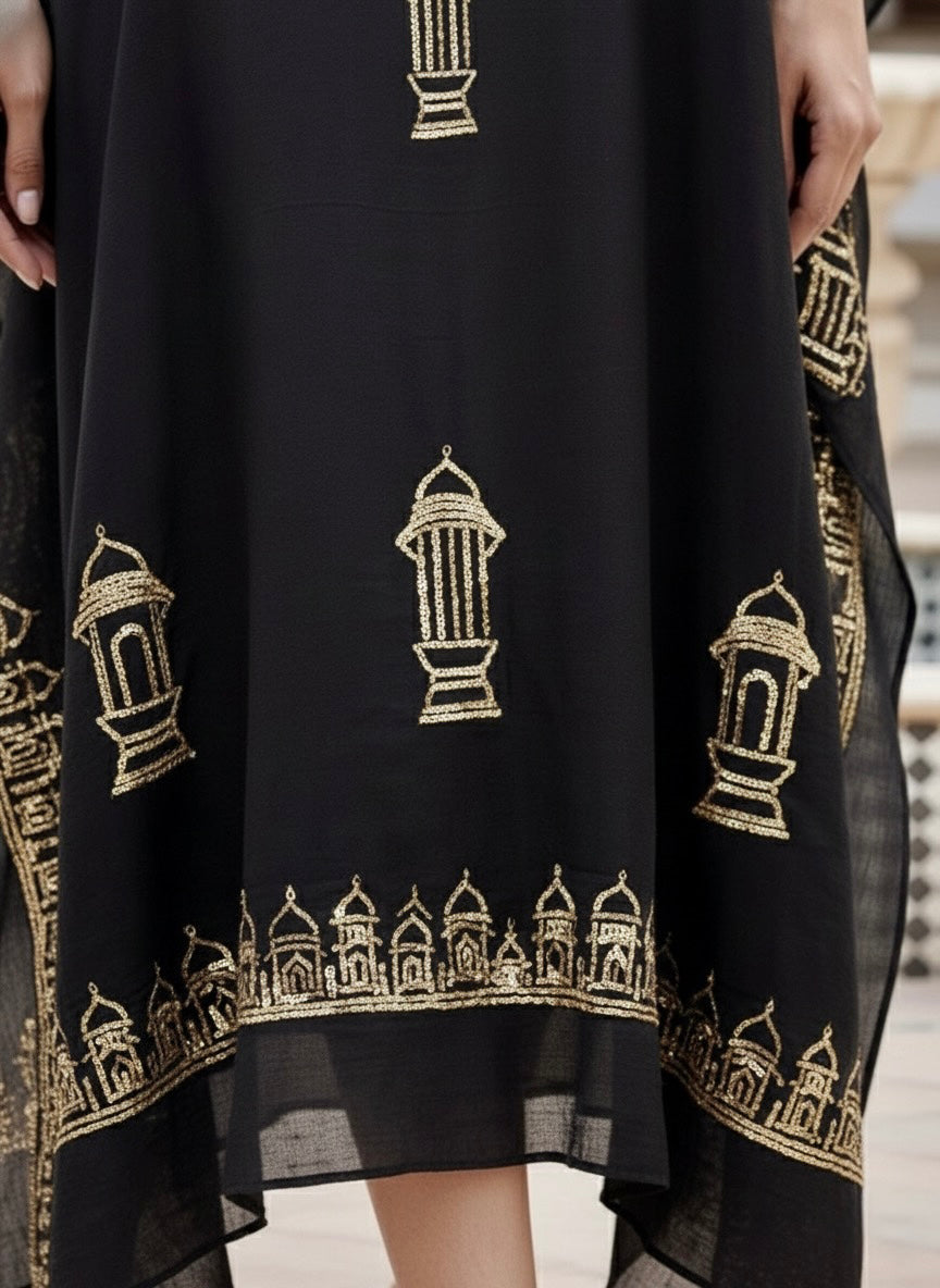 Woman wearing a black kaftan by Umaid Couture  with gold patterns in an outdoor setting