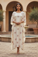 Woman in a floral kaftan standing in a courtyard with arches and a fountain. Product by Umaid Couture
