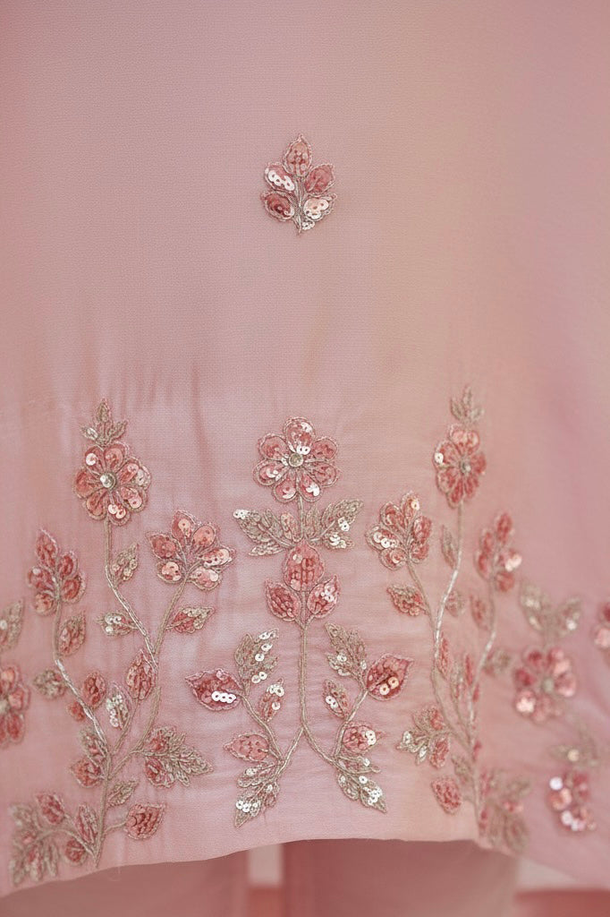 Pink fabric with floral embroidery and sequins on a light pink background. Product by Umaid Couture