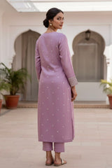 Woman wearing a lavender traditional outfit with white patterns in an indoor setting. Product by Umaid Couture