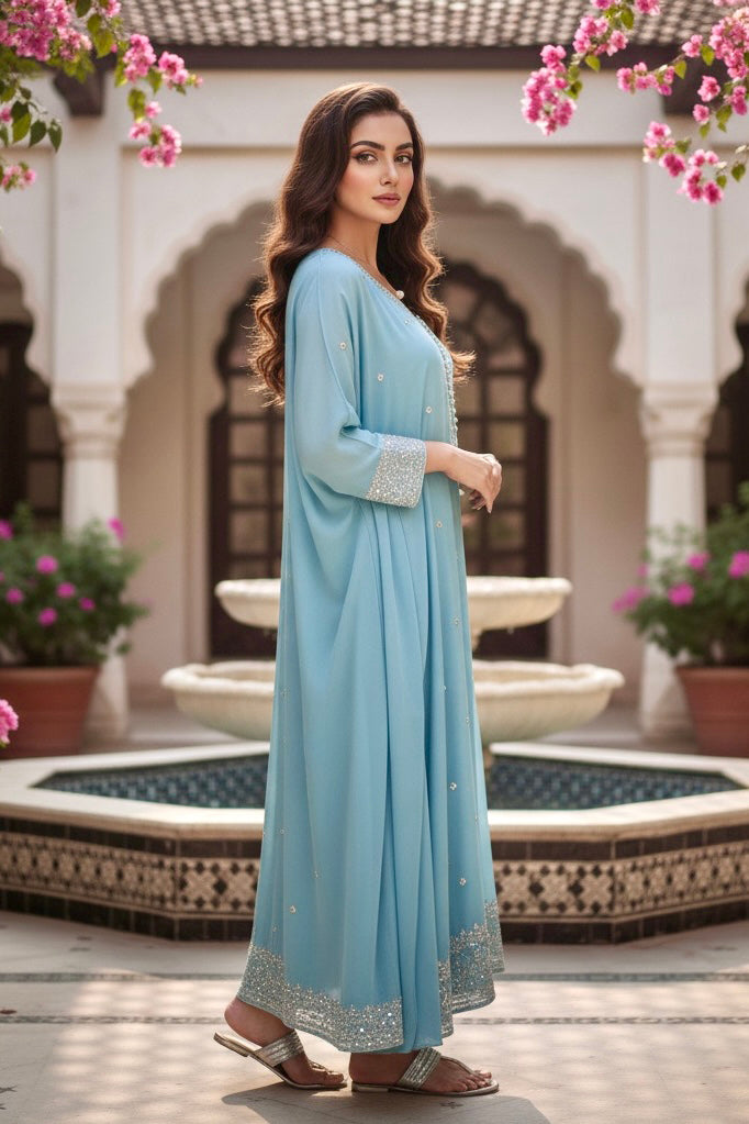 Woman in a light blue dress standing in front of a fountain with floral decorations. Product by Umaid Couture