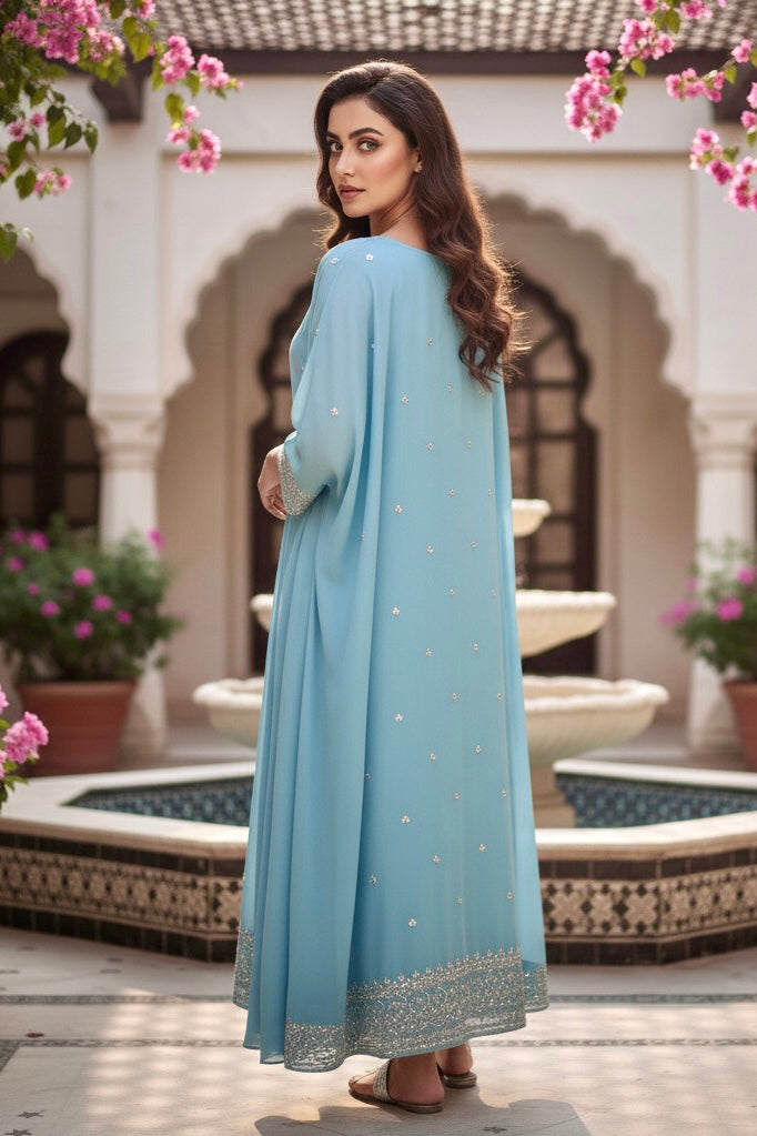 Woman in a light blue dress standing in front of a fountain with floral decorations. Product by Umaid Couture