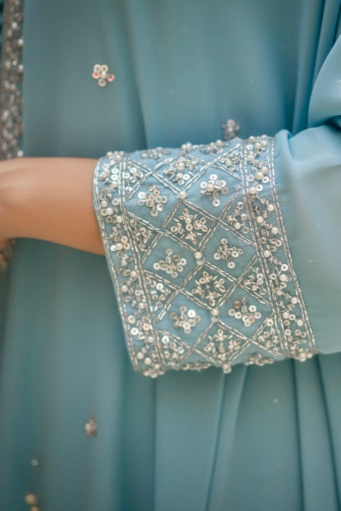 Close-up of a light blue dress with intricate silver beadwork on the cuffs. Product by Umaid Couture
