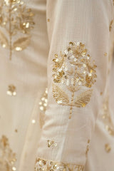 Close-up of a cream fabric with gold floral embroidery. Product by Umaid Couture