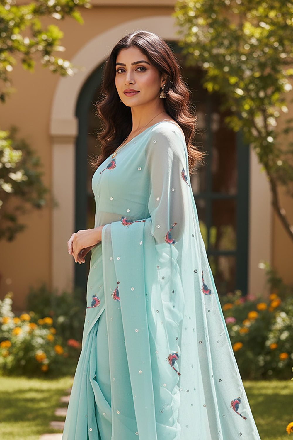 Woman wearing a light blue saree with Sparrow motifs saree from Umaid Couture, standing in a garden