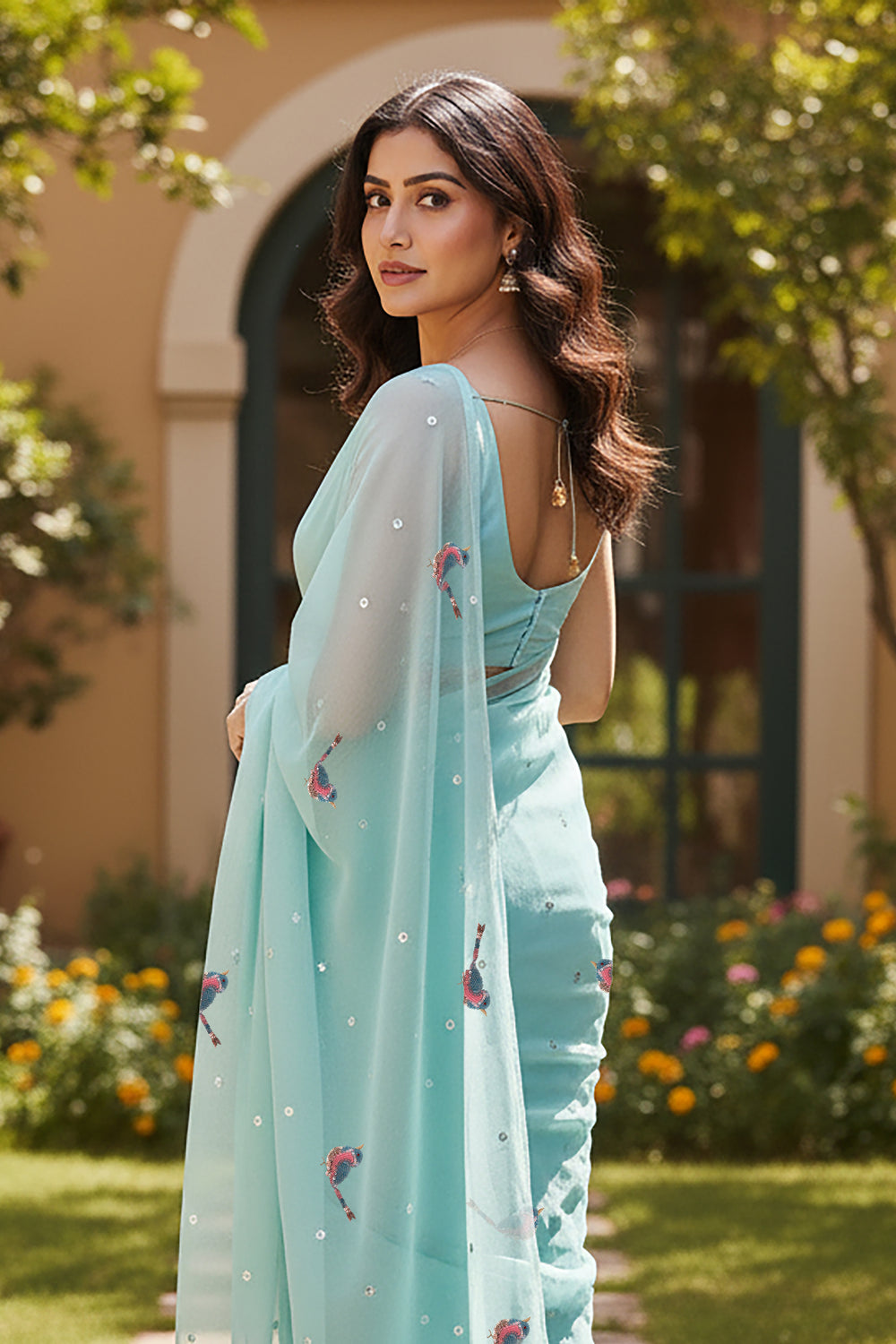 Woman wearing a light blue saree with Sparrow motifs saree from Umaid Couture, standing in a garden