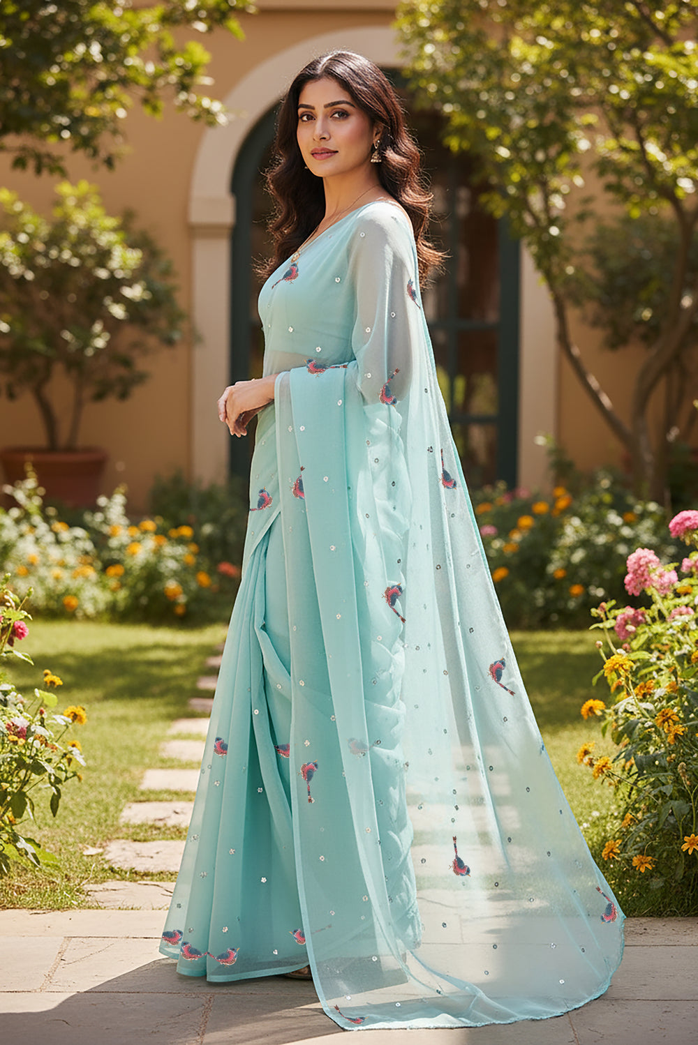 Woman wearing a light blue saree with Sparrow motifs saree from Umaid Couture, standing in a garden