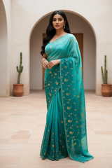 Woman wearing a teal saree by Umaid Couture with gold patterns in an indoor setting.