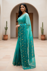 Woman wearing a teal saree by Umaid Couture with gold patterns in an indoor setting.
