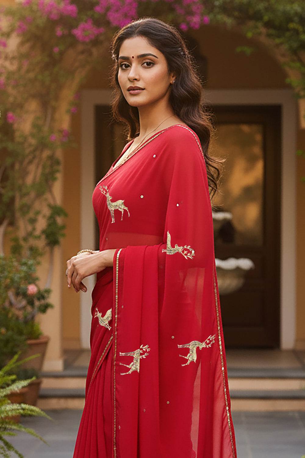 A woman in Red Caribou Golden Sequins Motif saree by Umaid Couture, standing in a Garden Courtyard