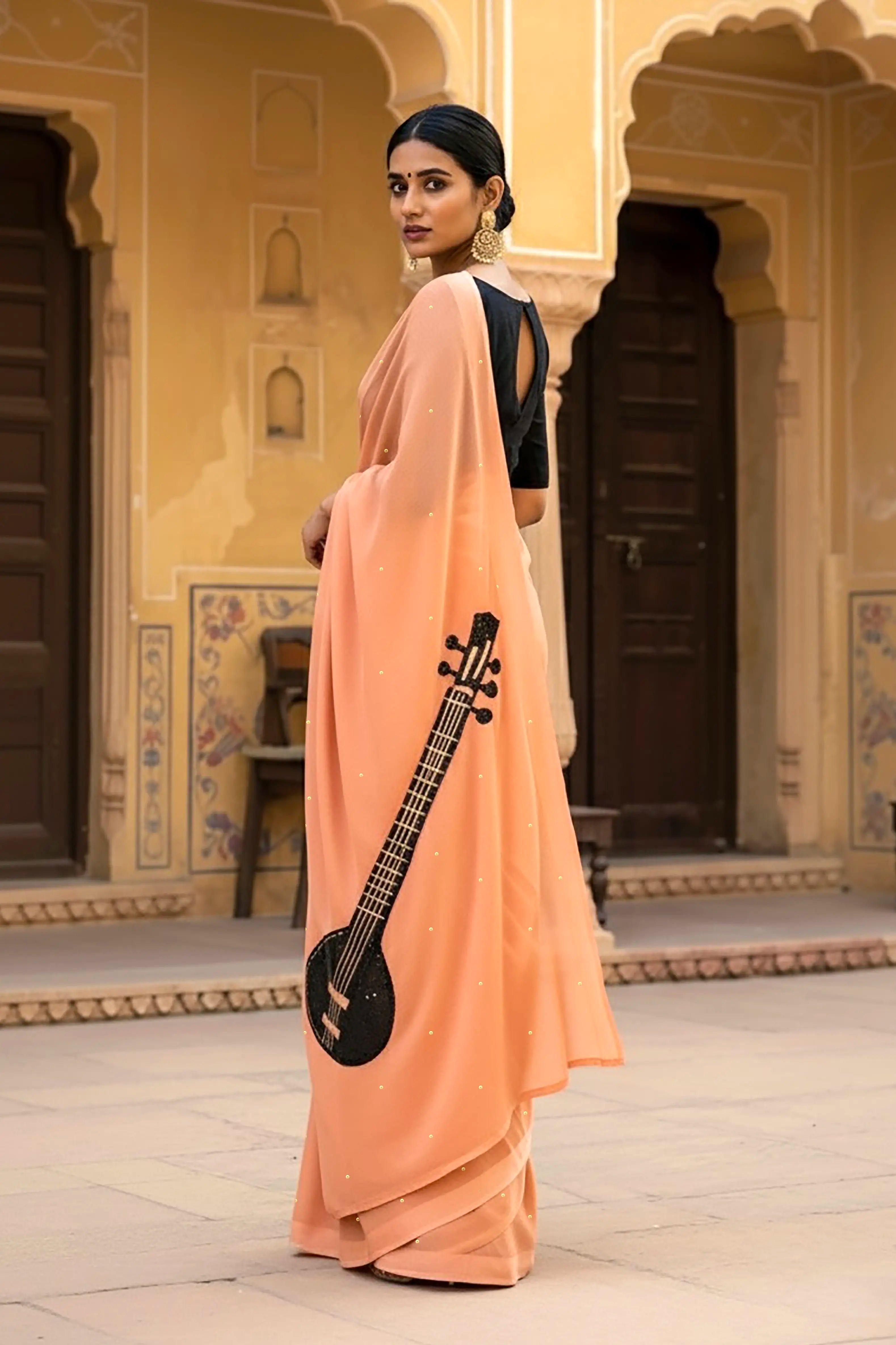 A woman in peach saree embellished with Sitar motif by Umaid Couture